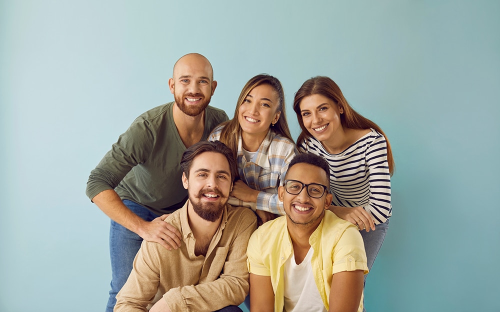 Group photo of the Movement Orthodontics team, five smiling individuals in casual outfits against a light blue background